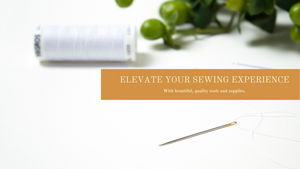 A hand-sewing needle, a spool of white thread and part of a plant on a white backbround. White text on an orange background appear near the centre read: "Elevate your sewing experience with beautiful, quality tools and supplies." Sewing supplies Canada.