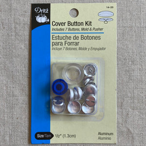 Dritz Cover Button Kit in it's package on a linen background. Kit includes 7 buttons, mold & pusher. Size is 1/2" or 1.3cm. Buttons are made of aluminum.